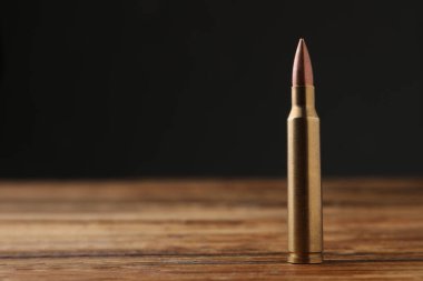 One bullet on wooden table. Space for text