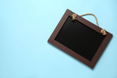 Açık mavi arka planda, temiz, küçük siyah karatahta, üst manzara. Metin için boşluk