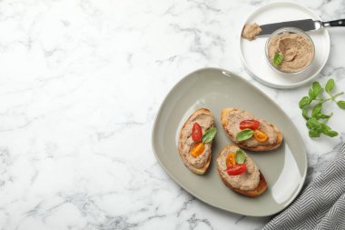 Lezzetli ezmeli ekmek dilimleri, beyaz mermer masada domates ve fesleğen, düz yatak. Metin için boşluk