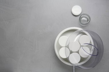 Açık gri masasında kavanozları olan modern yoğurt imalatçısı. Metin için boşluk