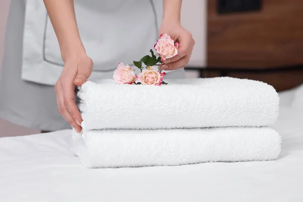 侍女在宾馆房间里的新鲜毛巾上放花 — 图库照片