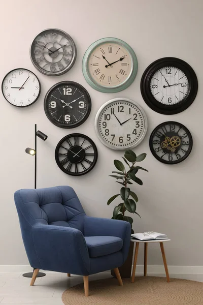 Armchair Table Many Different Clocks Hanging White Wall Room — Fotografia de Stock