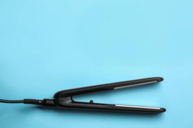 Açık mavi arka planda modern düz saç demiri, üst manzara. Metin için boşluk