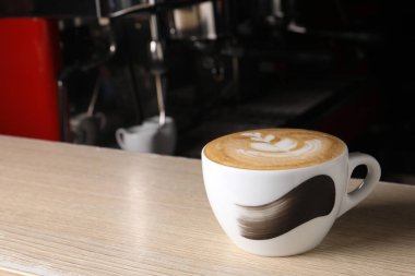 Cup of fresh aromatic coffee on wooden counter in cafe, space for text