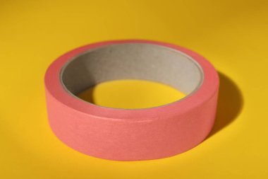 Sarı arkaplanda pembe yapışkan bant rulosu