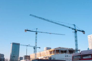 Güneşli bir günde inşaat vinçleri ve tamamlanmamış bina