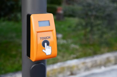 Orange traffic light push button on pillar outdoors