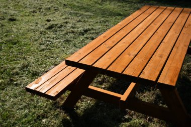 Empty wooden picnic table with bench outdoors on sunny day