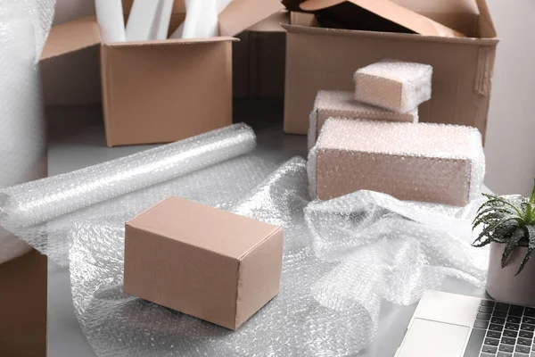 Table with laptop, boxes and bubble wrap in warehouse