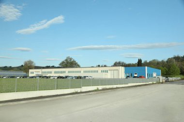 Güneşli bir günde etrafı çitlerle çevrili bir fabrika binası.