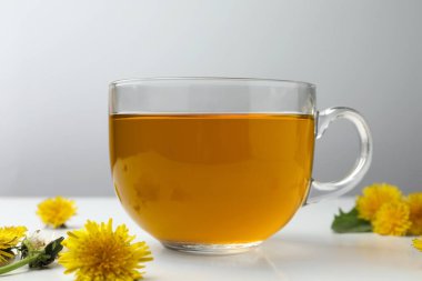 Lezzetli taze çay ve beyaz masada güzel karahindiba çiçekleri.