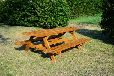 Güneşli bir günde parkta bankları olan boş ahşap piknik masası.