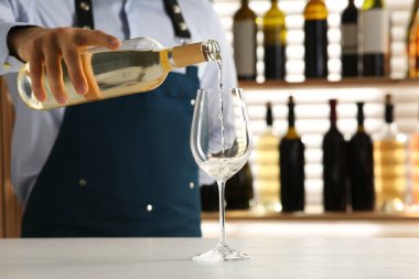 Barmen restoranda bardağa şarap dolduruyor.