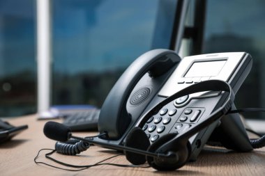 Sabit telefon ve kulaklık, ahşap masa içinde, yakın plan. Yardım hattı servisi