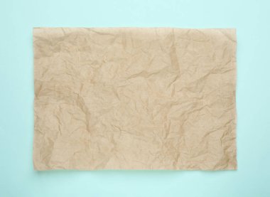 Açık mavi zemin üzerinde buruşuk kahverengi fırın kağıdı, üst görünüm