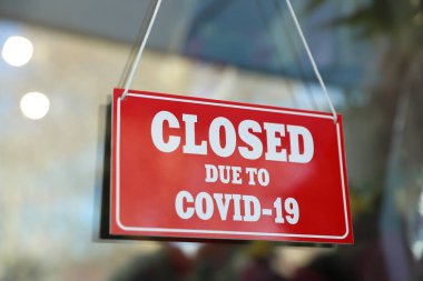 Camda asılı duran Covid-19 nedeniyle kapalı olan kırmızı tabela. Coronavirus karantinası
