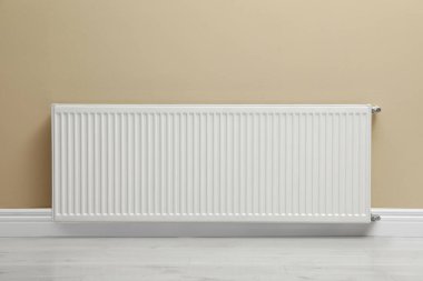 Modern radiator on beige wall indoors. Central heating system