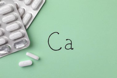 Açık yeşil arka planda kalsiyum takviye haplarıyla su toplamış.