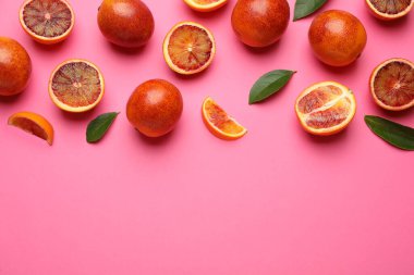 Birçok olgun Sicilya portakalı ve yaprakları pembe arka planda, düz yerde. Metin için boşluk