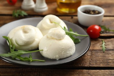 Ahşap masada roka ile nefis burrata peyniri, yakın plan.