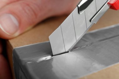 Paketi açmak için bıçak kullanan adam, yakın plan.