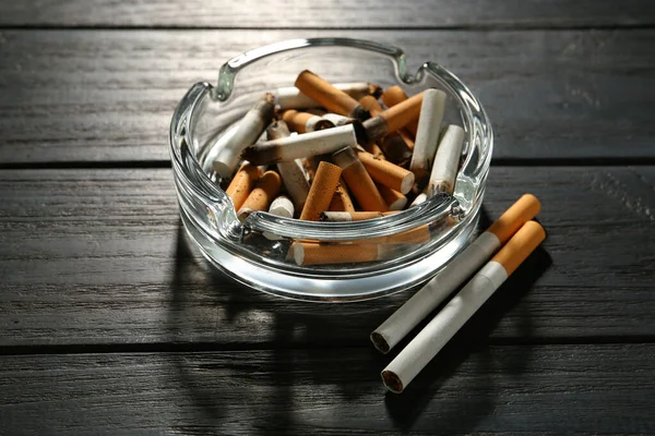 Skleněný Popelník Cigaretovými Pahýly Černém Dřevěném Stole — Stock fotografie