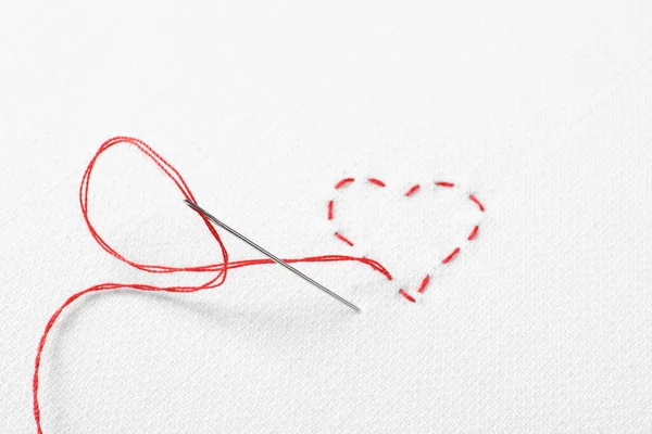 Βελόνα Κόκκινο Νήμα Και Ράμματα Σχήμα Καρδιάς Λευκό Ύφασμα Πάνω — Φωτογραφία Αρχείου