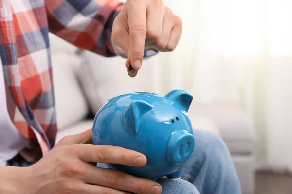 Man Putting Coin Piggy Bank Home Closeup — Foto de Stock