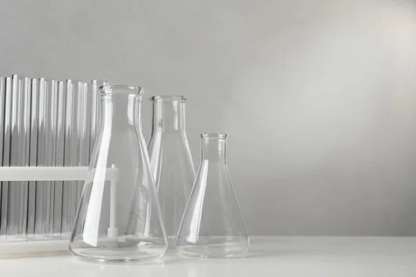 灰色の背景に白いテーブルの上の実験室用ガラス製品のセット テキストのためのスペース — ストック写真