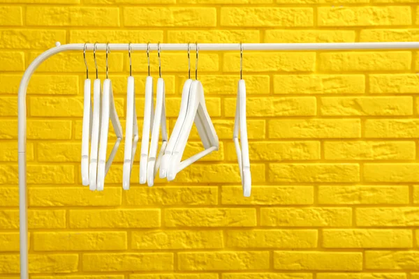 Kledingrek Met Veel Hangers Bij Gele Bakstenen Muur — Stockfoto