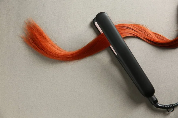 Modern Straightener Red Hair Lock Grey Background Top View — Foto Stock