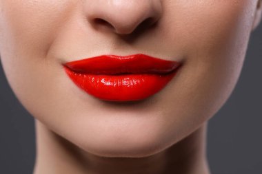 Gri arkaplanda güzel kırmızı dudakları olan genç bir kadın, yakın plan.