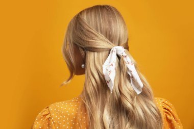 Sarı arka planda şık bandanalı genç bir kadın.