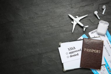 Pasaportlu düz kompozisyon, oyuncak uçak ve siyah masaya bilet, mesaj için yer. Vize alınıyor