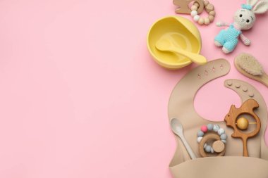 Pembe zemin üzerinde bebek aksesuarları ve önlüğü olan düz kompozisyon, metin için boşluk