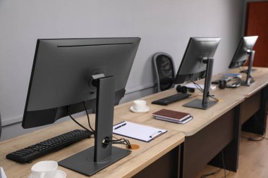 Ofisin içini aç. Açık gri duvarın yanında bilgisayarları olan modern işyerleri