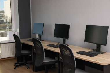 Ofisin içini aç. Açık gri duvarın yanında bilgisayarları olan modern işyerleri