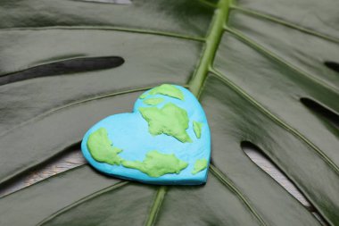 Dünya günün kutlu olsun. Yeşil yaprağın üzerindeki plastikten yapılmış gezegen, yakın plan.