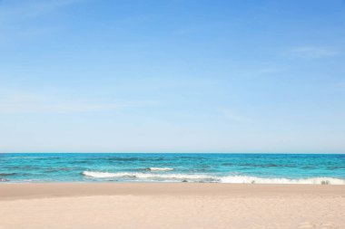 Güneşli bir günde güzel deniz ve kumlu plaj manzarası.