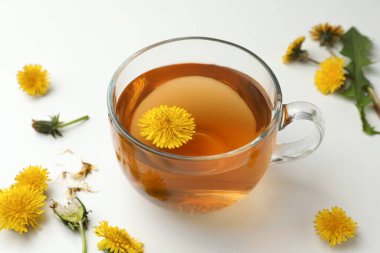 Lezzetli taze çay ve beyaz masada güzel karahindiba çiçekleri.