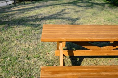 Empty wooden picnic table with bench in park on sunny day