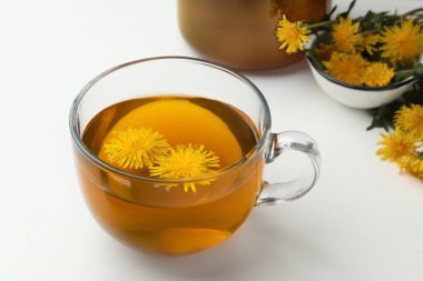 Lezzetli taze çay ve beyaz arka planda güzel karahindiba çiçekleri.