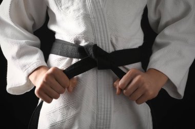 Man in keikogi with black belt on dark background, closeup. Martial arts uniform clipart