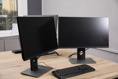 Modern iç mekan. Ofisteki ahşap masada çoklu monitörlü işyeri, mesaj için boşluk