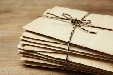 Stack of old letters tied with string on wooden table, closeup