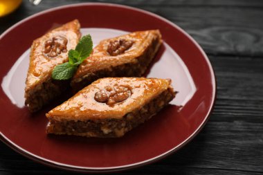 Cevizli ve nane şekerli lezzetli baklava siyah ahşap masa, yakın plan.
