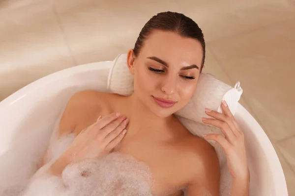 Young Woman Using Pillow While Enjoying Bubble Bath Indoors View — Stockfoto