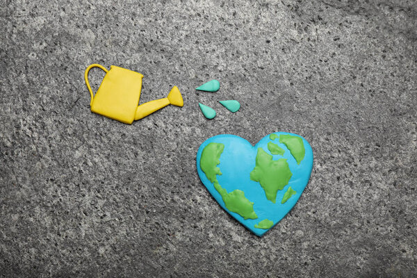 Happy Earth Day. Flat lay composition with plasticine planet and watering can on grey table