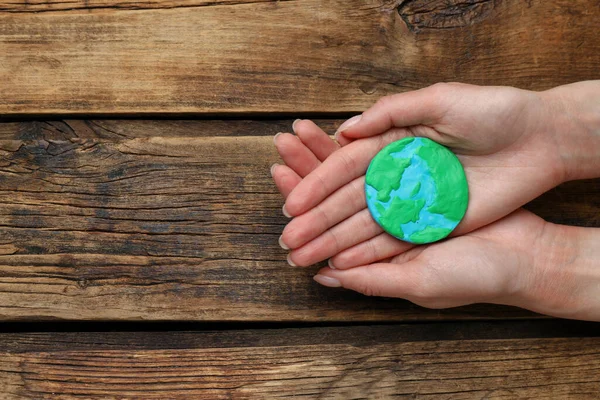 Happy Earth Day. Woman with plasticine planet at wooden table, top view and space for text