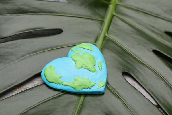 С Днем Земли. Планета из пластилина на зеленом листе, крупный план